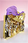 A small gold metallic gift bag with ribbons