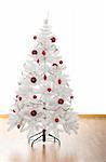 Christmas white tree with red ornaments in a house