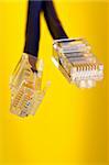 Two handing RJ-45 cables on yellow background