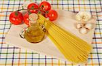 Tomatoes, olive oil, garlic and spaghetti, on the tablecloth