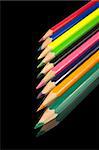 Assortment of coloured pencils with shadow on black background