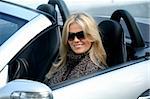 Blond girl in sunglasses driving convertable car