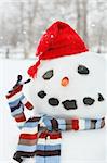 Building a snowman with red hat on a cold wintry day