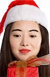 Asian girl in Santa hat looking on wrapped gift-box