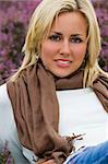 A beautiful blond haired blue eyed young woman laying amongst flowering heather.