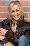 A beautiful, blue eyed young woman resting on an acoustic guitar.