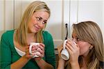 Two beautiful young women chatting over a warm drink.