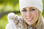 A stunningly beautiful young blond woman wrapped up warm smiling and surrounded by beautiful natural colours