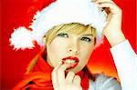 Portrait of beautiful blond young woman wearing santa claus hat on red background