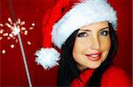 Portrait of beautiful brunette woman wearing santa claus hat on red background