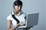 Beautiful brunette business woman with wireless headset and laptop computer isolated on clear background