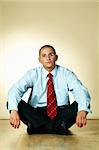 A businessman is sitting on wooden floor