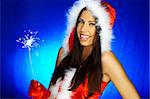 Portrait of beautiful brunette woman wearing sexy santa claus hat on blue background