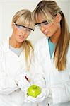 Female scientists injecting liquid into a apple