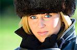 A beautiful young blonde woman with Blue eyes wrapped up warm and bathed in winter sunshine