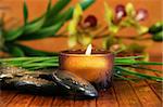 Amber candle and spa stones with orchid  on bamboo