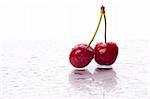 Two cherries, with water droplets, with reflection. Landscape framing.