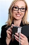 A smiling business woman using her portable pda device to organise her life and access business related software.