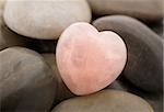 Rose quartz heart on pebbles
