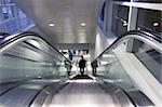 This is a 1 point perspective of a business guy traveling down an escalator.