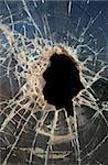 Hole smashed in thick,dirty glass with dark background