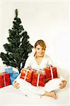 Young beautiful woman next to christmas tree and presents