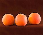 Three Ripe Organic Apricots On Brown Backround ~ Natural Light