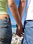 Summer love - Detail of young couple holding hands on beach background