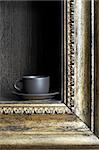 Black cup on a shelf in the form of a frame