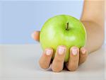 Close-up of a female hand holding a green apple