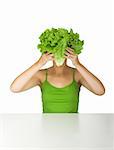 Woman in green holding a lettuce in front of the face