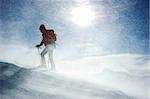 A lonely backcountry skier reaching the summit of the mountain during a snowstorm, horizontal orientation