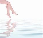 Beautiful woman legs reflected on clear water surface. Copy space, white background.