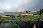 Houseboats in Srinigar, Kashmir (India) - after a light rain a rainbow appears in the distance with mountains as the backdrop.