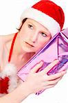 Beautiful girl dressed in a christmas lingerie set holding a present up to her ear. With clipping path for your convenience.