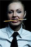 Beautiful business woman wearing black tie and white shirt isolated on black background holding pencil in her mouth