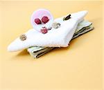 Spa essentials (cream, white towel and pink flowers) isolated on yellow