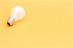 Background with lit lightbulb. Isolated on yellow