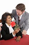 An attractive interracial couple on a date.  He surprises her with a red rose.