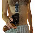 Cropped shot of a male hand holding a .38 calibre with a condom on it and hairy chest in the background. Front shot with white background.