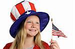A pretty little girl in a patriotic American hat holding a flag and looking into the distance.