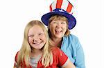 A mother and daughter dressed for fourth of july.  The focus is on the mother in the hat, laughing.  Isolated on white.