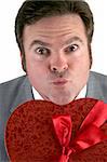 A closeup photo of a man holding a box of valentine candy and puckering up for his valentines day kiss.