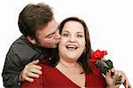 Man surprises his date by giving her a rose and a kiss.  Isolated on white.