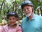 An attractive senior couple wearing bike helmets.