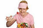 A senior woman in pink with Breast Cancer Awareness ribbon, eating healthy salad.  Isolated on white.