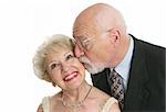 A pretty senior woman giggling as her husband surprises her with a kiss.