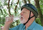 A senior man drinking water after riding his bike.