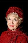 A beautiful senior lady in red sweater and hat.  Black background.