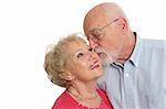 An attractive senior man kissing his beautiful wife on the cheek.  Isolated with room for text.